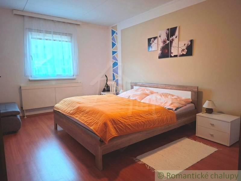 Veľkorysý 10-árový pozemok, slnečná nehnuteľnosť, priestranné bývanie  - Spálňa v rodinnom dome s posteľou, dekoráciou a podlahou s dreveným dekorom.