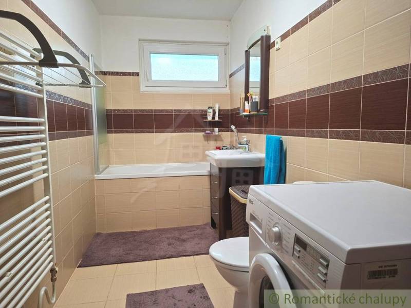 Veľkorysý 10-árový pozemok, slnečná nehnuteľnosť, priestranné bývanie  - Kúpeľňa v rodinnom dome s vaňou, práčkou a hnedo-béžovým obkladom.