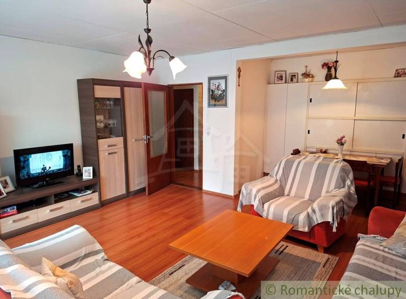 Veľkorysý 10-árový pozemok, slnečná nehnuteľnosť, priestranné bývanie  - Obývačka v rodinnom dome s pohodlnými sedačkami a podlahou s dreveným dekorom.