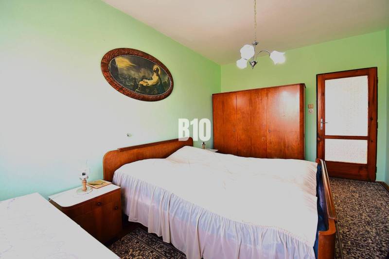 5 izbový  rodinný dom vo Varíne - Spálňa v rodinnom dome s masívnym dreveným nábytkom a dekoratívnym obrazom na stene.