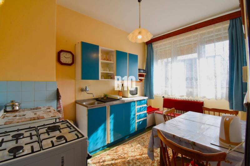 5 izbový  rodinný dom vo Varíne - Kuchyňa v rodinnom dome s modrou linkou, plynovým sporákom a jedálenským stolom.