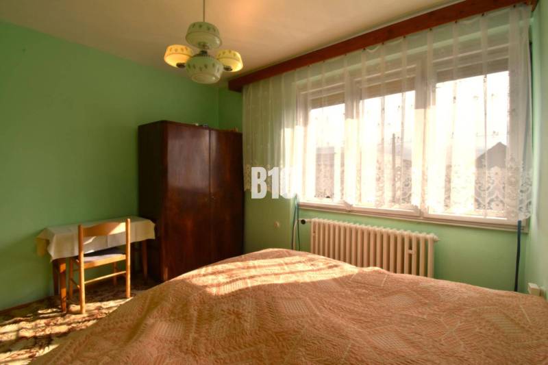 5 izbový  rodinný dom vo Varíne - Spálňa v rodinnom dome s oknom, záclonami, skriňou a stolom.