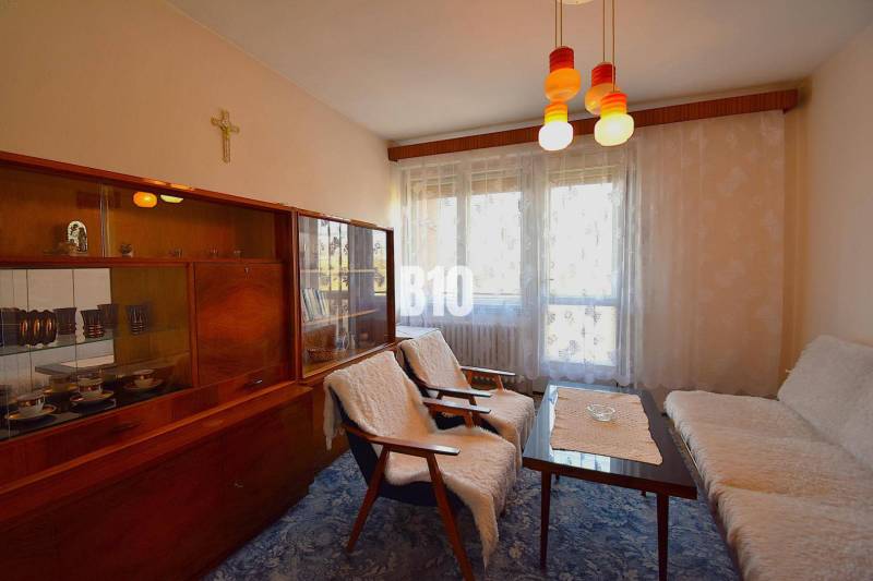 5 izbový  rodinný dom vo Varíne - Obývacia izba v rodinnom dome s retro nábytkom a závesmi na okne.