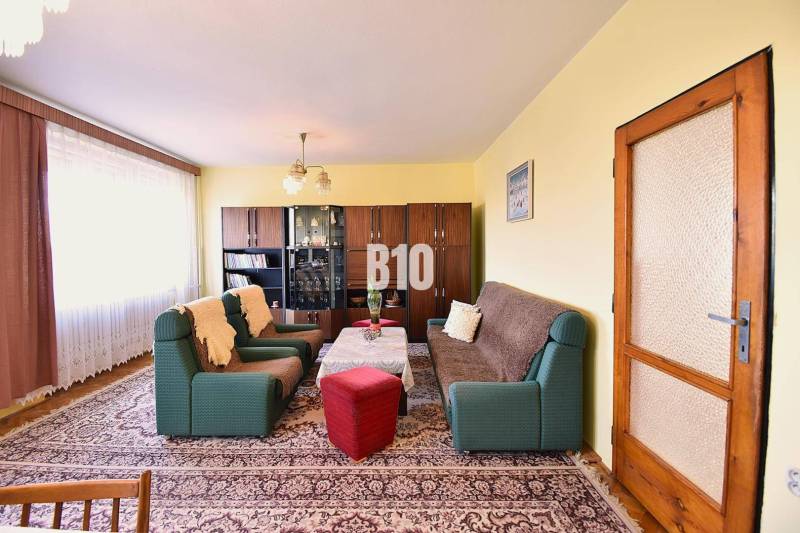 5 izbový  rodinný dom vo Varíne - Obývačka v rodinnom dome s pohovkami, kreslami, vitrínou a kobercom.