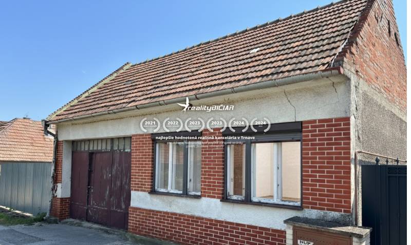 Veľkorysý pozemok s obrovským potenciálom v Dolných Orešanoch - Rodinný dom v Dolných Orešanoch na ulici Dolné Orešany, s červenou tehlovou fasádou.