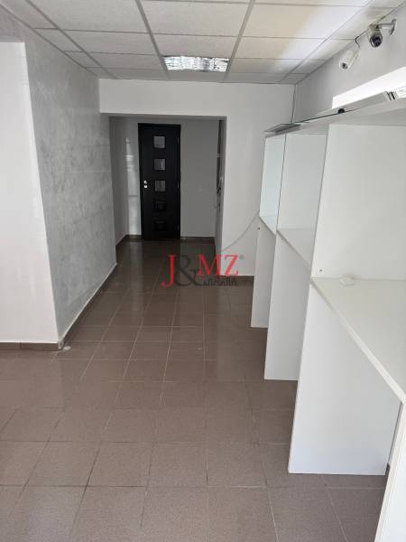 Obchodný priestor, kancelária Sarartovská ul.  - Interiér obchodných priestorov s policami, dvermi a sivou podlahou s lesklým povrchom.