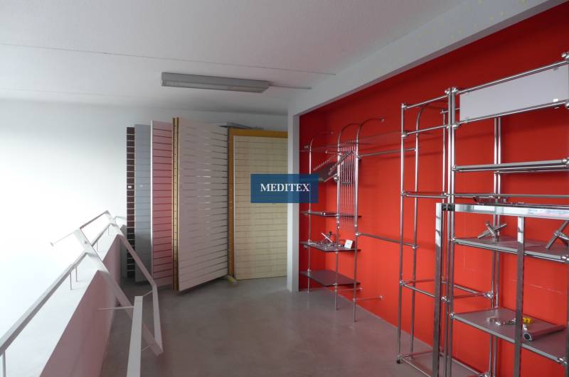 Obchodný priestor na prenájom pri ceste o ploche  372 m2  - Predajňa s kovovými regálmi a stojanmi v obchodných priestoroch.