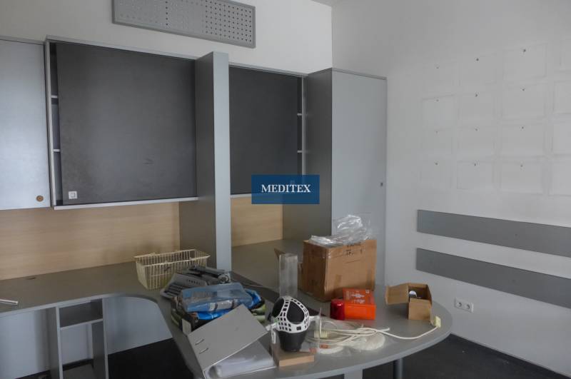 Obchodný priestor na prenájom pri ceste o ploche  372 m2  - Kancelária s úložnými skrinkami a stolom, na ktorom sú rôzne predmety.
