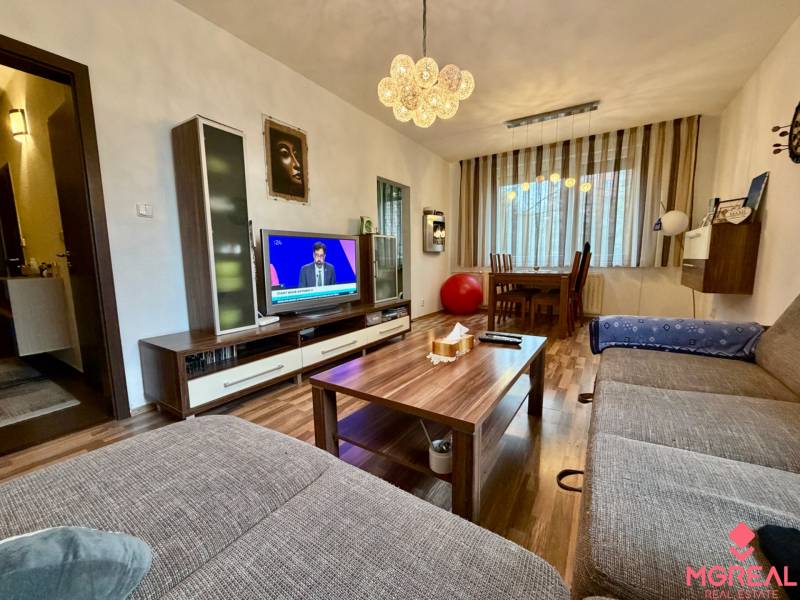 3 izbový byt  Topoľčany blízko centra - Obývacia izba v 3-izbovom byte s podlahou s dreveným dekorom a pohodlným gaučom.