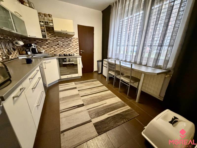 3 izbový byt  Topoľčany blízko centra - Kuchyňa v 3-izbovom byte s tmavou podlahou a veľkým oknom.