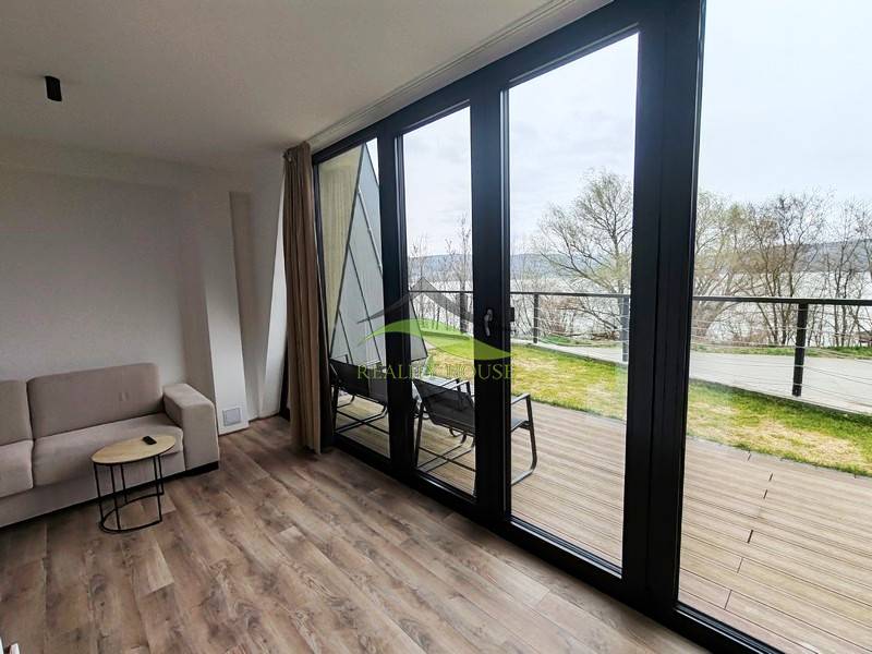 Luxusná Apartmánová chata Domaša Eva: Airbnb Hit! - Interiér chaty s pohovkou, podlaha s dreveným dekorom, veľké okná s výhľadom na terasu.