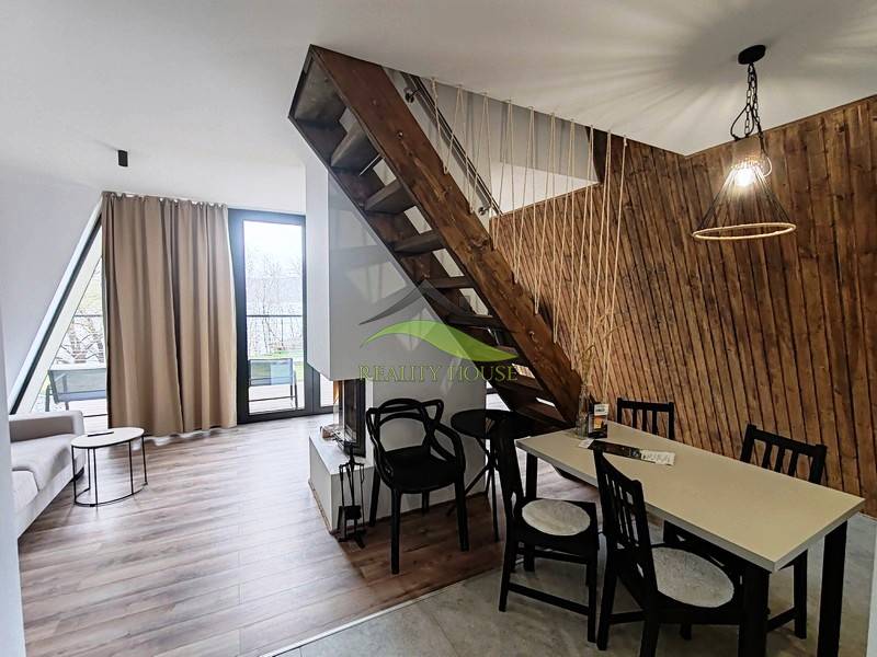 Luxusná Apartmánová chata Domaša Eva: Airbnb Hit! - Chata s podlahou s dreveným dekorom, schodiskom a stolom vedľa steny z drevených lamiel.