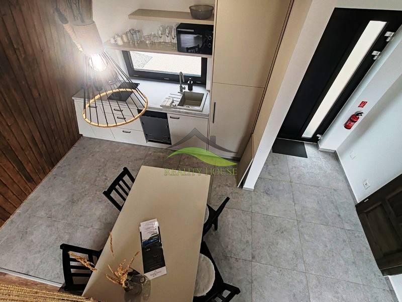 Luxusná Apartmánová chata Domaša Eva: Airbnb Hit! - Interiér chaty s jedálenským stolom, kuchynskou linkou a dreveným dekorom podlahy.