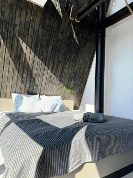 Luxusná Apartmánová chata Domaša Eva: Airbnb Hit! - Posteľ s pruhovanou prikrývkou a drevenými stenami v Chate.