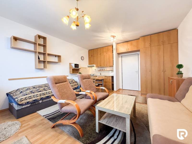 Na prenájom garsónka 30m2, Východná - Trenčín - Garsónka s podlahou s dreveným dekorom, sedačkou, kreslami a vstavanou skriňou.