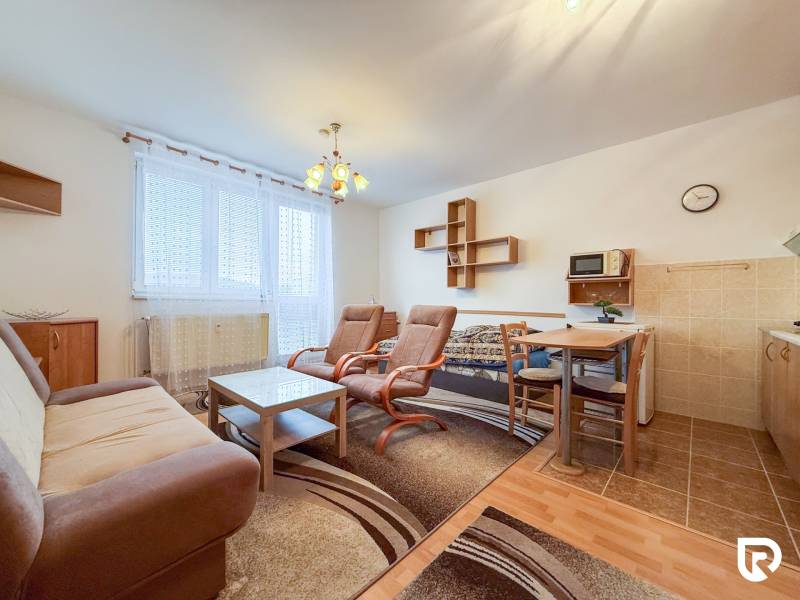 Na prenájom garsónka 30m2, Východná - Trenčín - Garsónka s podlahou s dreveným dekorom, gaučom, kreslami, stolom a kuchynským kútom.