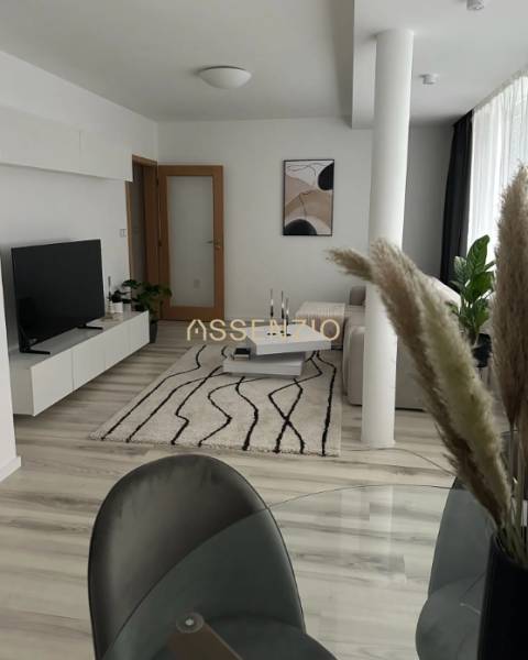 - PRENÁJOM - 2 IZBOVÝ BYT - DOLNÁ UL. - STARÉ MESTO - Obývačka 2-izbového bytu s podlahou s dreveným dekorom, bielym nábytkom a kobercom.