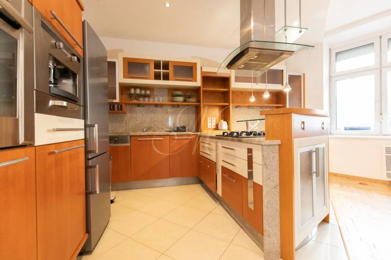 Priestranný 4-izbový byt s predzáhradkou, Staré Mesto - Kuchyňa v 4-izbovom byte s dreveným dekorom a spotrebičmi z nehrdzavejúcej ocele.