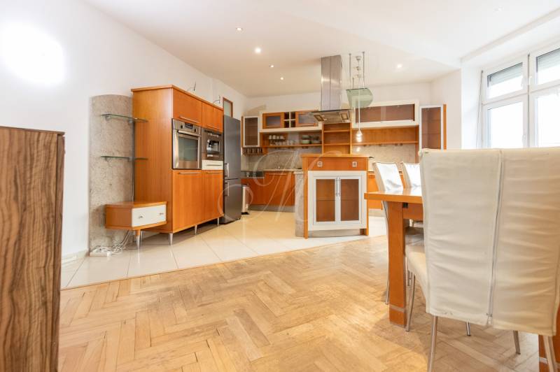 Priestranný 4-izbový byt s predzáhradkou, Staré Mesto - Kuchyňa v 4-izbovom byte s podlahou s dreveným dekorom a zabudovanými spotrebičmi.