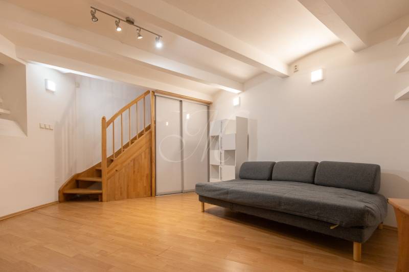 Priestranný 4-izbový byt s predzáhradkou, Staré Mesto - Obývacia izba s pohovkou a schodiskom, podlaha s dreveným dekorom, 4-izbový byt.