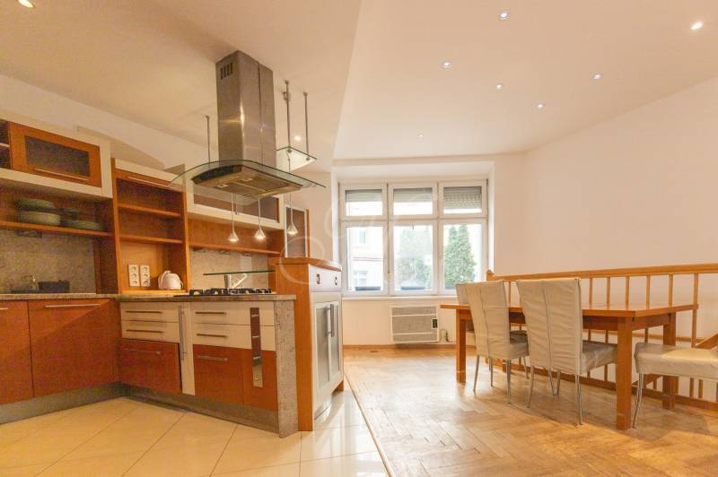 Priestranný 4-izbový byt s predzáhradkou, Staré Mesto - Kuchyňa s jedálenským kútom v 4-izbovom byte, podlaha s dreveným dekorom, biela stena.