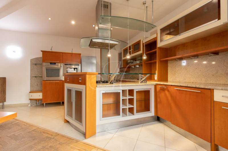 Priestranný 4-izbový byt s predzáhradkou, Staré Mesto - Kuchyňa v 4-izbovom byte s ostrovčekom a podlahou s dreveným dekorom.