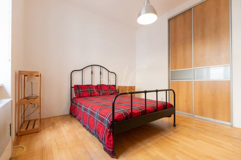 Priestranný 4-izbový byt s predzáhradkou, Staré Mesto - Spálňa v 4-izbovom byte s kovovou posteľou, šatníkovou skriňou a podlahou s dreveným dekorom.