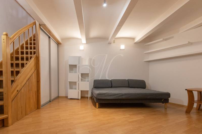 Priestranný 4-izbový byt s predzáhradkou, Staré Mesto - Obývacia izba s pohovkou, schodmi a podlahou s dreveným dekorom v 4-izbovom byte.