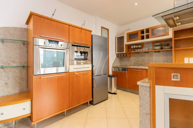 Priestranný 4-izbový byt s predzáhradkou, Staré Mesto - Kuchyňa v 4-izbovom byte s nerezovým spotrebičmi a drevenými skrinkami.