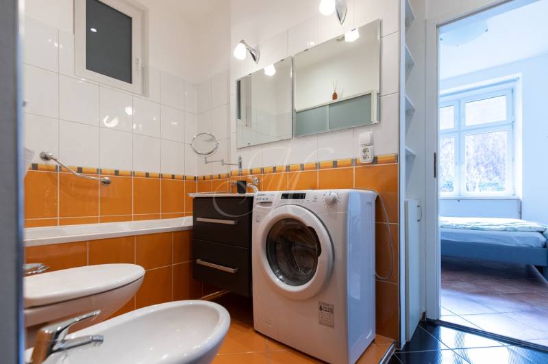 Priestranný 4-izbový byt s predzáhradkou, Staré Mesto - Kúpeľňa so vstavanou práčkou a oranžovým obkladom v 4-izbovom byte.