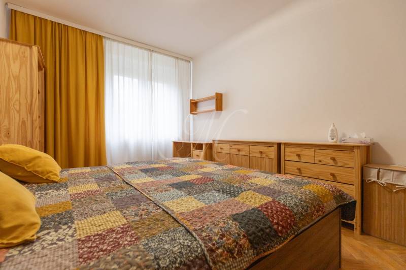 2-izbový byt s balkónom, Ružinov – Ostredky - Spálňa v 2-izbovom byte so žltými závesmi a nábytkom z dreva.