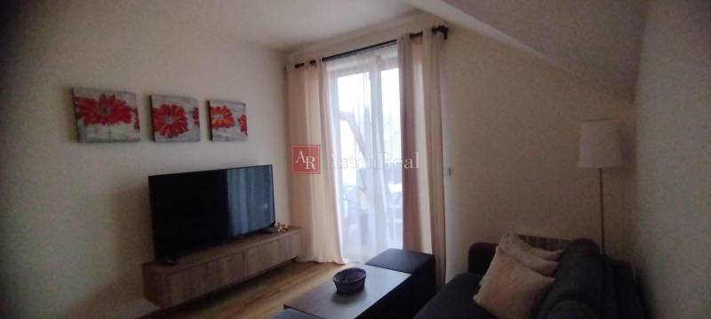 Predaj !Elegantný byt s wellness prvkami pri Jasnej - Obývacia izba v 2-izbovom byte s podlahou s dreveným dekorom, dekoráciou a televízorom.