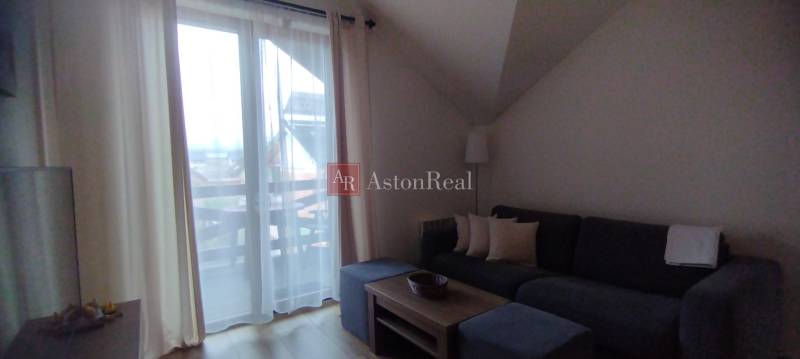 Predaj !Elegantný byt s wellness prvkami pri Jasnej - Obývacia izba v 2-izbovom byte s pohovkou, konferenčným stolíkom a výhľadom na balkón.