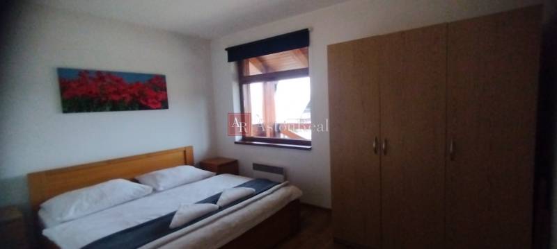 Predaj !Elegantný byt s wellness prvkami pri Jasnej - Spálňa s manželskou posteľou, podlahou s dreveným dekorom a šatníkovou skriňou v 2-izbovom byte.