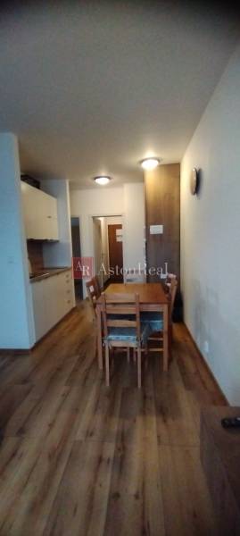 Predaj !Elegantný byt s wellness prvkami pri Jasnej - Jedáleň v 2-izbovom byte s podlahou s dreveným dekorom a dreveným stolom.