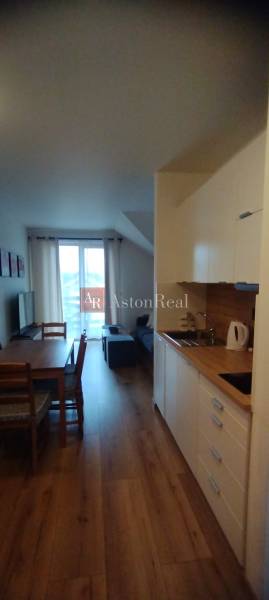 Predaj !Elegantný byt s wellness prvkami pri Jasnej - Kuchynský kút a jedálenský stôl so stoličkami, 2-izbový byt, podlaha s dreveným dekorom.