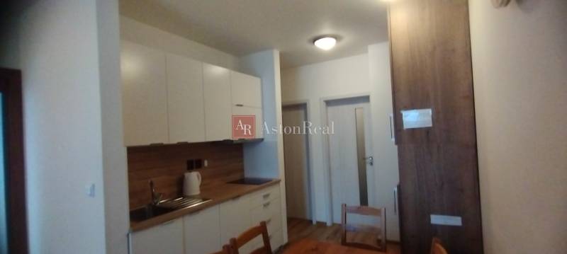 Predaj !Elegantný byt s wellness prvkami pri Jasnej - Kuchyňa v 2-izbovom byte s podlahou s dreveným dekorom a bielymi skriňami.