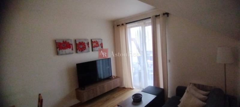 Predaj !Elegantný byt s wellness prvkami pri Jasnej - Obývacia izba s pohovkou, televízorom a červenými obrazmi v 2-izbovom byte.