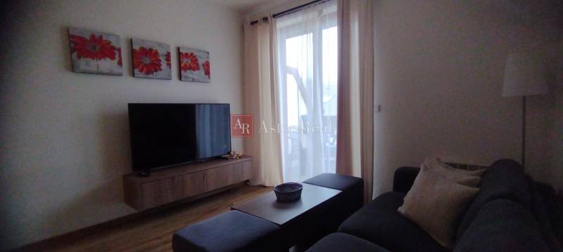 Predaj !Elegantný byt s wellness prvkami pri Jasnej - Obývacia izba s televízorom, podlahou s dreveným dekorom a pohodlným gaučom v 2-izbovom byte.