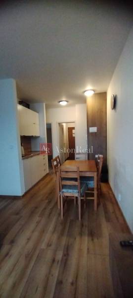 Predaj !Elegantný byt s wellness prvkami pri Jasnej - Interiér 2-izbového bytu s podlahou s dreveným dekorom a jedálenským stolom.