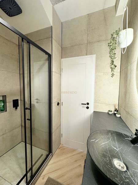 - PRENÁJOM - 3 IZBOVÝ BYT - WILSONOVA UL. - STARÉ MESTO - Kúpeľňa v 3-izbovom byte s čiernym umývadlom, sprchovým kútom a podlahou s dreveným dekorom.