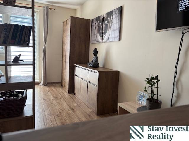 Exkluzívny investičný apartmán/byt  na predaj v srdci Donovál  - Interiér 1-izbového bytu s nábytkom z dreveným dekorom a umením na stene.