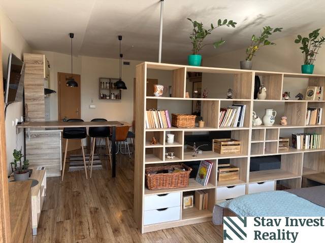 Exkluzívny investičný apartmán/byt  na predaj v srdci Donovál  - Interiér 1-izbového bytu s podlahou s dreveným dekorom a otvorenou kuchyňou.