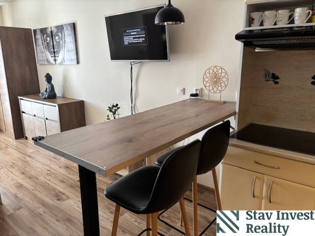 Exkluzívny investičný apartmán/byt  na predaj v srdci Donovál  - Jedálenský pult v 1-izbovom byte s podlahou s dreveným dekorom a moderným nábytkom.