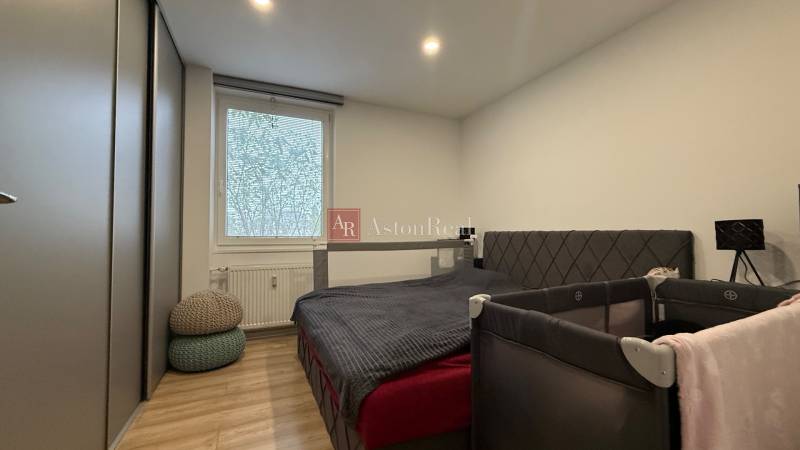 KOMPLETNE prerobený 4i byt s balkónom, 77m2 - ZÁTVOR - Spálňa v 4-izbovom byte s posteľou, skriňou a dreveným dekorom podlahy.