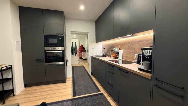 KOMPLETNE prerobený 4i byt s balkónom, 77m2 - ZÁTVOR - Kuchyňa v 4-izbovom byte s tmavými skriňami a podlahou s dreveným dekorom.