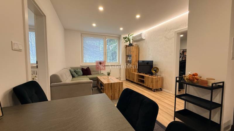 KOMPLETNE prerobený 4i byt s balkónom, 77m2 - ZÁTVOR - Obývacia izba so sedačkou, TV a dekorom na podlahe v 4-izbovom byte.