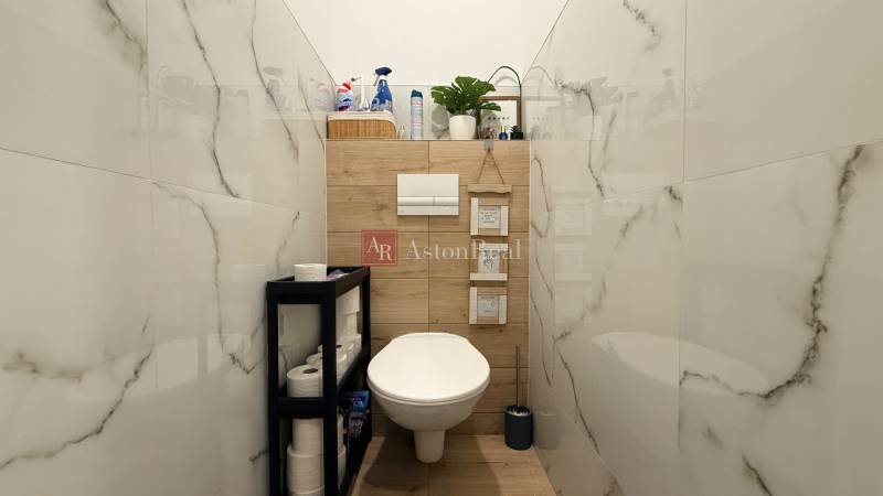 KOMPLETNE prerobený 4i byt s balkónom, 77m2 - ZÁTVOR - Kúpeľňa so závesným WC, dreveným dekorom a úložným regálom v 4-izbovom byte.