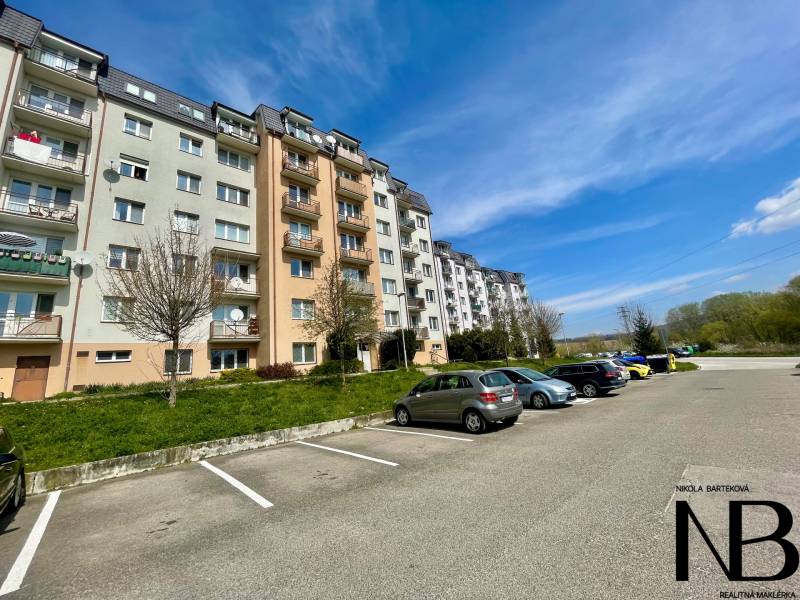 Na prenájom slnečný 2i byt s balkónom, ul. Východná, Trenčín - Bytovka na ulici Východná, parkovisko, stromy, 2-izbový byt, modrá obloha, auto.