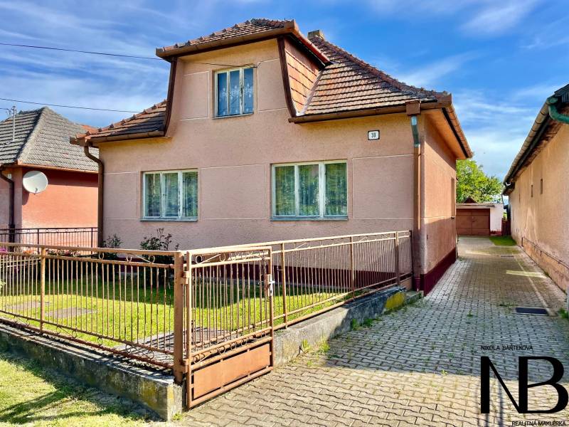 Rodinný dom s veľkým pozemkom a garážou, Dvorec - Rodinný dom vo Dvorci so šikmou strechou a vstupnou bránou.